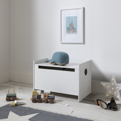 A white toy box toy storage organiser placed in a contemporary room setting with children's toys around it.