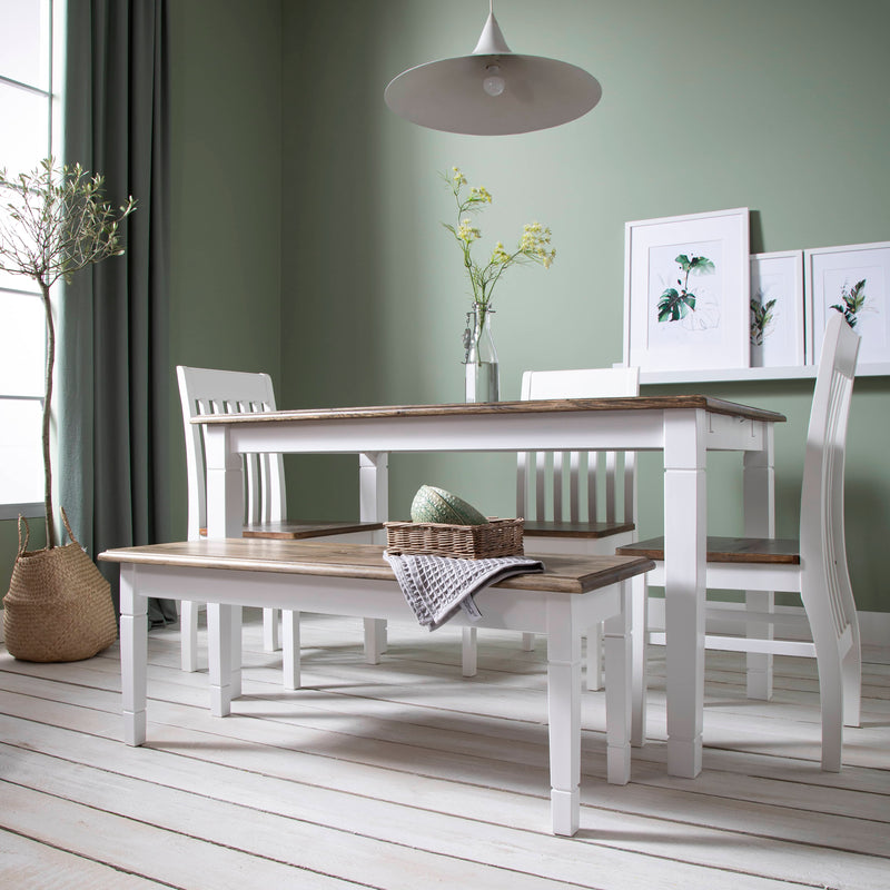 Dining room with a white table and chairs against a green wall.