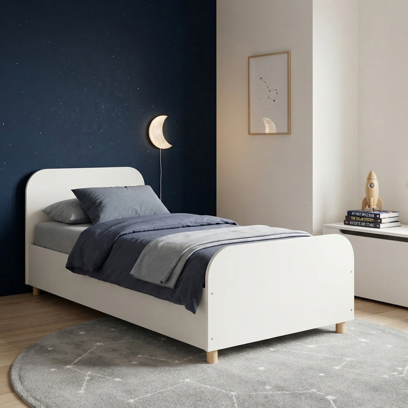 White bed with gray bedding in a bedroom setting with a dark blue wall and framed picture.