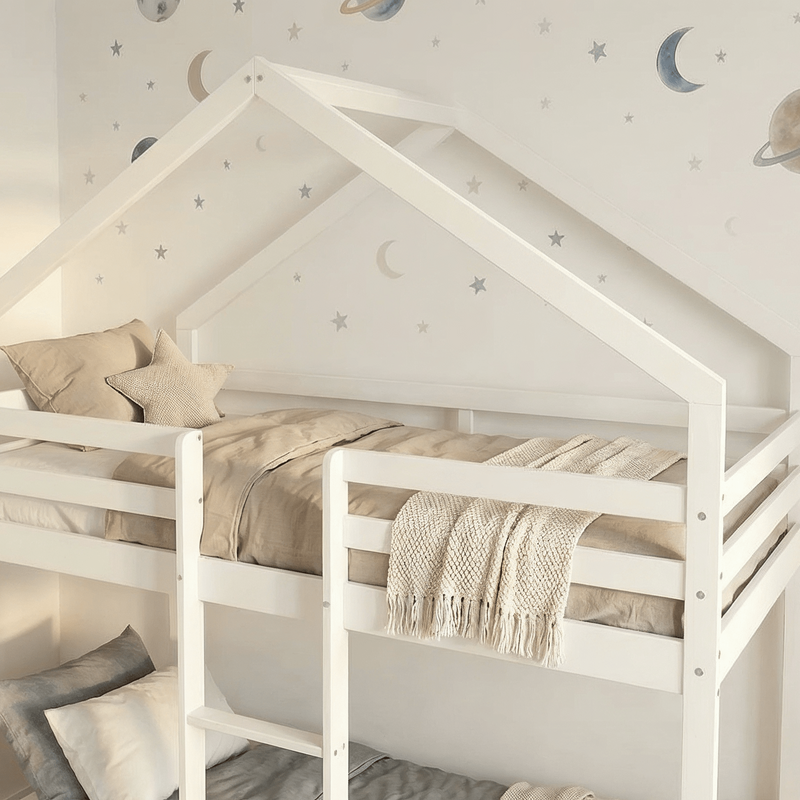 White children's bed with beige bedding against a wall with space-themed decorations.